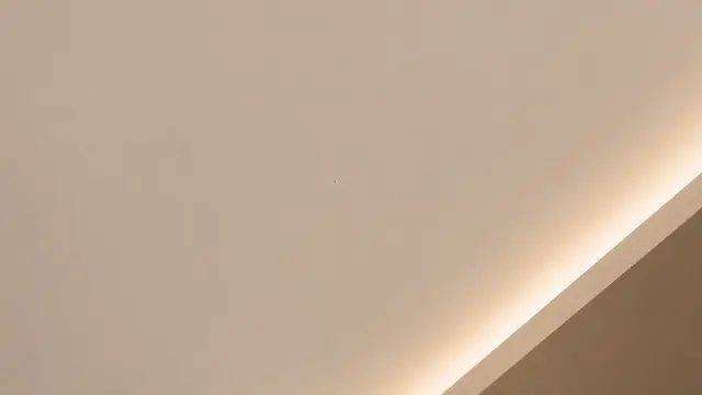 Close-up of a clean white gypsum false ceiling with a soft microfibre cloth and a long-handled duster on a step ladder below, daylight